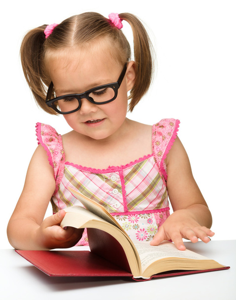 Little girl is flipping over pages of a book - Foto, afbeelding
