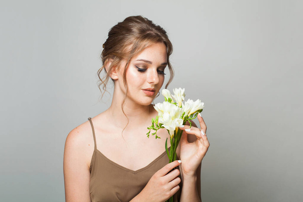Vonzó barna nő gyönyörű virágokkal. Csinos nő természetes smink és friss bőr - Fotó, kép