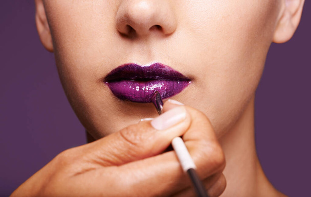 Lipstick, beauty and mouth of woman on purple background for makeup, cosmetics and products. Salon aesthetic, creative and closeup of lips of person with lipgloss, shine and cosmetics in studio. - Photo, Image