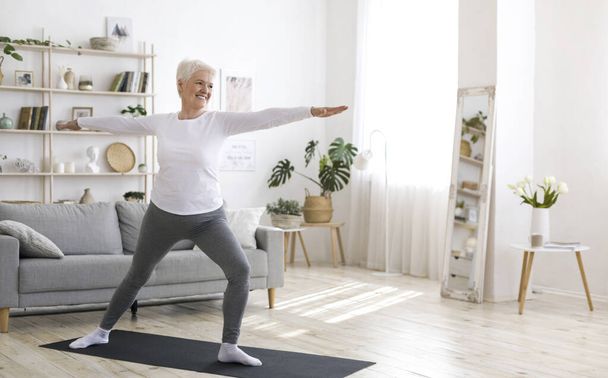 Sport na emeryturze. Aktywny starszy kobieta robi ćwiczenia Pilates w domu, szkolenia w salonie podczas kwarantanny - Zdjęcie, obraz