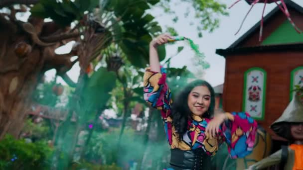 Hymyilevä nuori nainen värikkäässä puserossa poseeraa ulkona kaupunkitaustan kanssa päivänvalossa - Materiaali, video