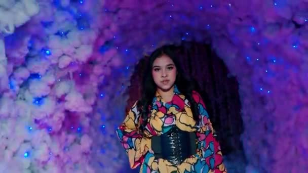 Radosna młoda kobieta tańcząca na imprezie z kolorowym oświetleniem i bokeh tle w nocy - Materiał filmowy, wideo