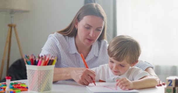 Kadın ve genç çocuk renkli kalemlerle birlikte resim yapıyorlar. Evde eğitim kavramı. Yüksek kalite 4k görüntü - Video, Çekim