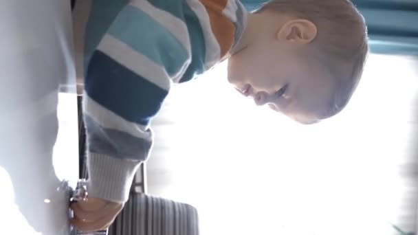 In the mesmerizing light contrasts, a little boy finds joy as he playfully engages with his toys on a table in the comfort of his home Vertical footage. - Footage, Video