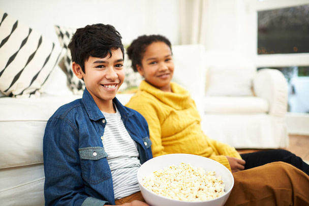 Happy family, love and popcorn in portrait in home and relax for bonding together on vacation. Brother, sister and positive face of siblings by couch, floor and snack on school holiday in living room. - Photo, Image