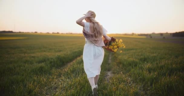 Girato di una donna vibrante che corre attraverso un pittoresco campo di semi oleosi, catturando energia e vitalità tra fioriture dorate - Filmati, video