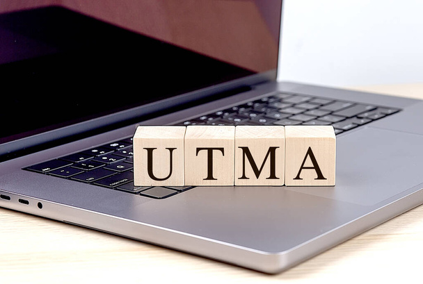 Слово UTMA на дерев'яному блоці на ноутбуці, бізнес-концепція.  - Фото, зображення