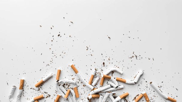 Відкинуті подрібнені сигарети і розкидані тютюни на білому тлі, що представляють припинення і кінець куріння з копіювальним простором. Немає тютюнового дня. Високоякісна фотографія - Фото, зображення
