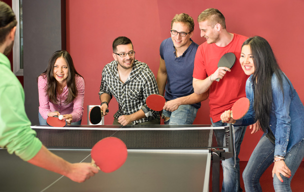 Groep gelukkige jonge vrienden spelen ping pong tafeltennis - leuk moment in spelletjeskamer van reiziger Jeugdherberg - Concept van vintage sport en echte emoties - Main focus op twee jongens met bril - Foto, afbeelding