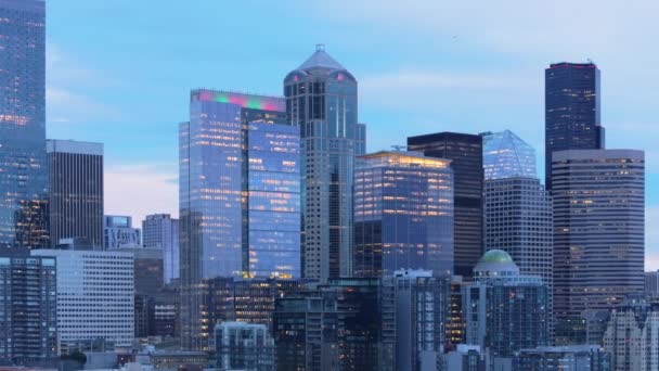 Crepúsculo desciende sobre Seattle, iluminando los interiores de los rascacielos y creando un cuadro vibrante con la arquitectura de las ciudades en contra de un cielo nocturno tranquilo. Imágenes 4K.  - Metraje, vídeo