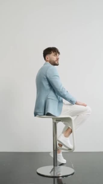 Mann im blauen Anzug sitzt auf Hocker - Filmmaterial, Video