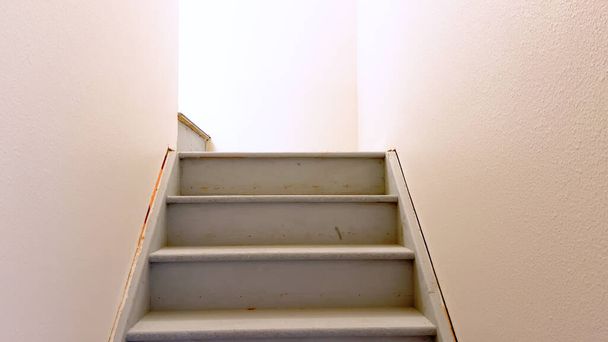 清潔なラインとミニマリスティックなデザインが特徴の,家の地下に降りてくる平らな白い絵の階段の眺め. - 写真・画像