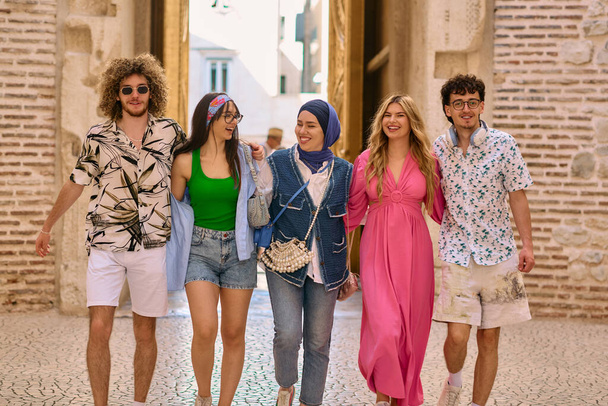 Různorodá skupina turistů, oblečená v letních šatech, se prochází turistickým městem se širokými úsměvy a vychutnává si jejich vyhlídkové dobrodružství.  - Fotografie, Obrázek