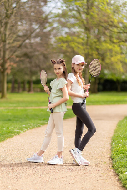 Dvě dívky pózující s badmintonovými raketami v parku. - Fotografie, Obrázek
