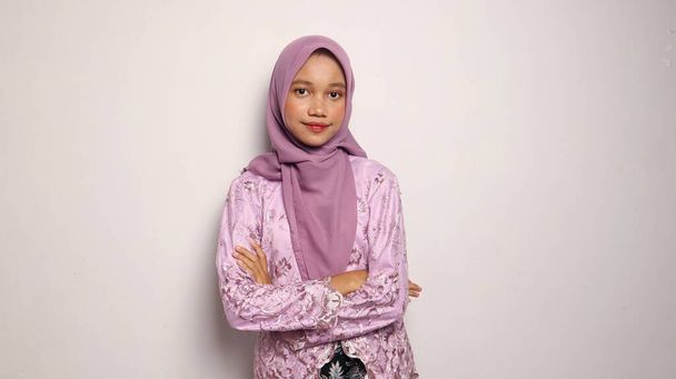 インドネシアの十代の少女はケバヤとヒジャブでドレスアップし,孤立した白い背景と笑顔を楽しみにしています - 写真・画像