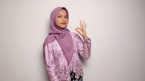 usmívající se indonéské dospívající dívky na sobě kebaya a hidžáb gestikulace v pořádku na izolovaném bílém pozadí - Fotografie, Obrázek