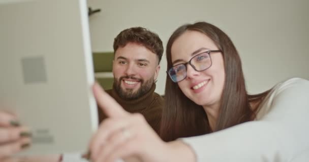 Un dipendente uomo e donna condividono un momento gioioso durante una pausa ufficio, sorridendo e facendo segni di pace mentre si scattano un selfie, evidenziando il loro cameratismo e l'ambiente di lavoro positivo.. - Filmati, video