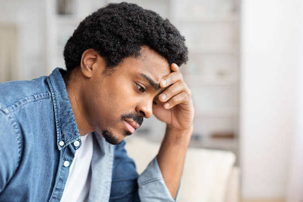 With visible distress or shame, a black guy covers his face with his hands while at home, suggesting despair, privacy concerns or a moment of intense emotions - Photo, Image