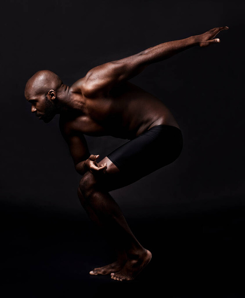 Cuerpo, estiramiento y hombre sobre fondo oscuro con salud, bienestar y fitness o listo para correr en el estudio. Joven, atleta o modelo africano en art deco para danza, entrenamiento o musculación. - Foto, imagen