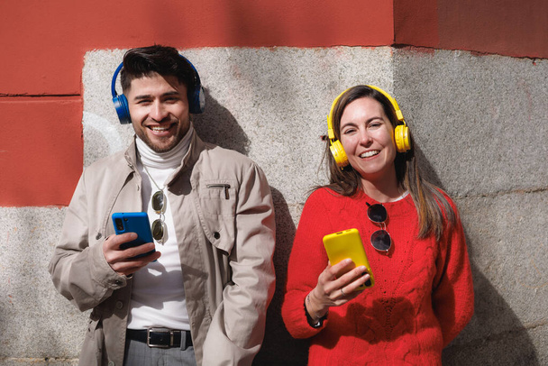 Retrato de un par de amigos latinos usando el teléfono celular y escuchando música. Generación Z. Foto de alta calidad - Foto, imagen