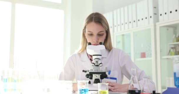 Two chemist or medical scientists work together in a laboratory and discuss the result of an analysis on a microscope. Scientific research of bacteria viruses and teamwork - Footage, Video