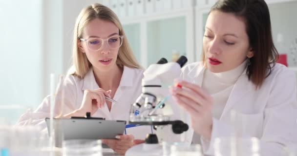 Dois cientistas químicos de laboratório trabalham juntos em um laboratório e soltam o líquido azul no vidro de um microscópio. Medicina química experimental em laboratório moderno - Filmagem, Vídeo