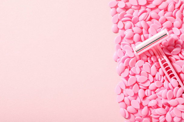 Voskové granule pro depilaci s břitvou na růžovém pozadí - Fotografie, Obrázek