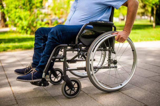 Закрыть изображение человека в инвалидной коляске, катящегося по дорожке в парке. - Фото, изображение