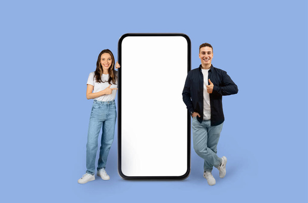 Fiatal férfi és nő áll egy hatalmas mobil mockup képernyő másolás hely reklám, stúdió háttér - Fotó, kép