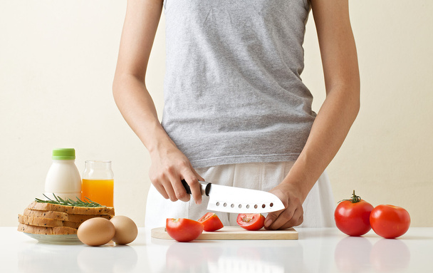 Young woman preparing breakfast, tomato eegs bread onion milk orange juice - Photo, Image