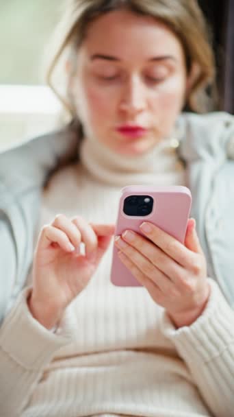 Vrouw in jasje bladert door haar telefoon in een café - Video