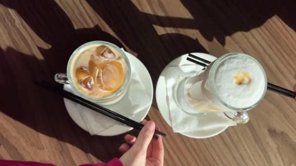 σερβιτόρος σερβίρει δύο lattes, ζεστό και κρύο, συγκρίνοντας τις δύο γεύσεις Ice latte και ζεστό αργά - Πλάνα, βίντεο