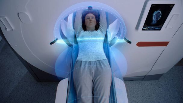 La patiente subit une IRM ou une tomodensitométrie, couchée sur un lit se déplaçant à l'intérieur. Effets visuels de scanner le cerveau et le corps de la femme. Réalité augmentée high-tech et équipement futuriste en clinique avancée. - Photo, image