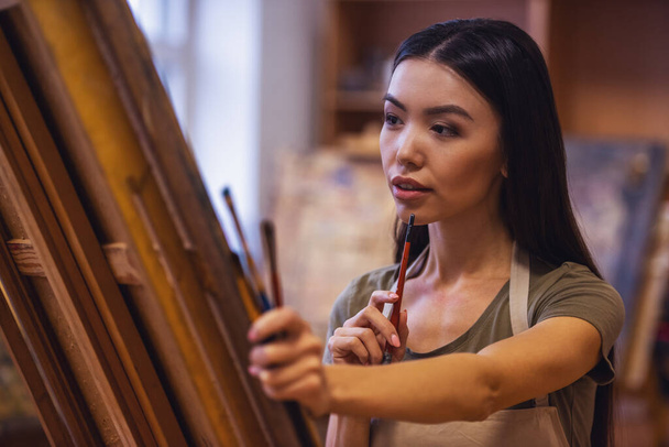 Молодая красивая женщина - художник живописи во время работы в студии
 - Фото, изображение