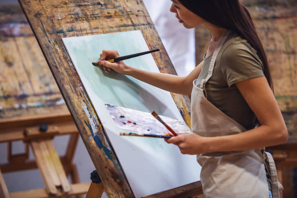 Молодая красивая женщина - художник живописи во время работы в студии
 - Фото, изображение