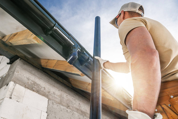 Trabajador de tejado de construcción Instalación de canales de la casa en la casa de ladrillos de hormigón recién desarrollado - Foto, Imagen