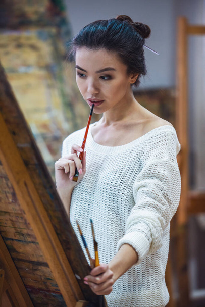 Egy fiatal gyönyörű nő, a festõ dolgozva egy stúdió - Fotó, kép