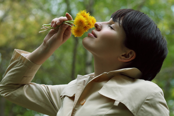 Красива жінка пахне квітами в парку
 - Фото, зображення