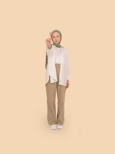 Мусульманська жінка, яка показує попередження знак зупинки пальцем, повна довжина тіла серйозна впевнена мусульманська жінка в Абхаї хіджаб показує знак зупинки пальцем. Стоїть над бежевим тлом, копіює простір. - Фото, зображення