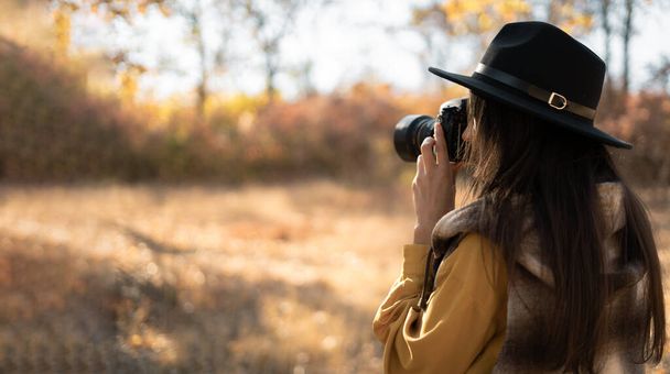 Mulher fotógrafa em um chapéu fotografando a natureza de outono. Viagens e conceito de hobby. Espaço de cópia - Foto, Imagem