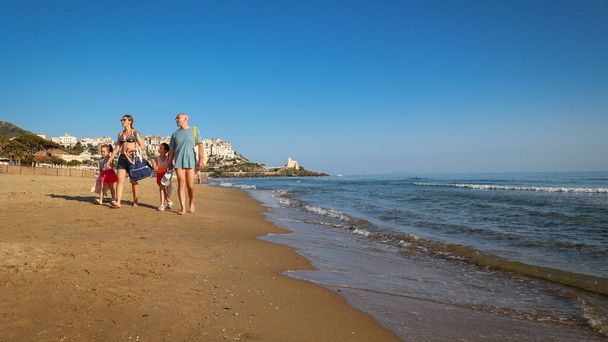 Сперлонга (LT), Італія 28 квітня 2024: Сім'я в купальниках гуляє в групі на пляжі в сонячний весняний день. - Фото, зображення