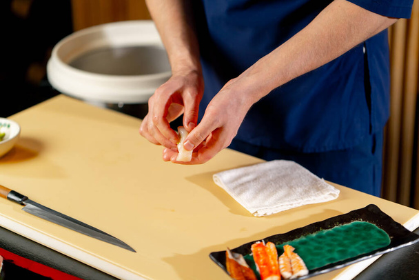 Nahaufnahme in einem japanischen Restaurant legt der Koch rohe Fischstücke auf einen Teller - Foto, Bild