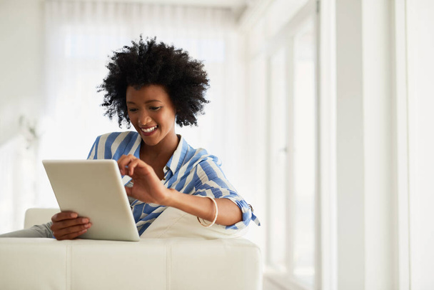 Black woman, home and happy sofa with tablet for social media post and entertainment. Female person, living room and couch on internet for streaming service or website for news update or funny videos. - Photo, Image