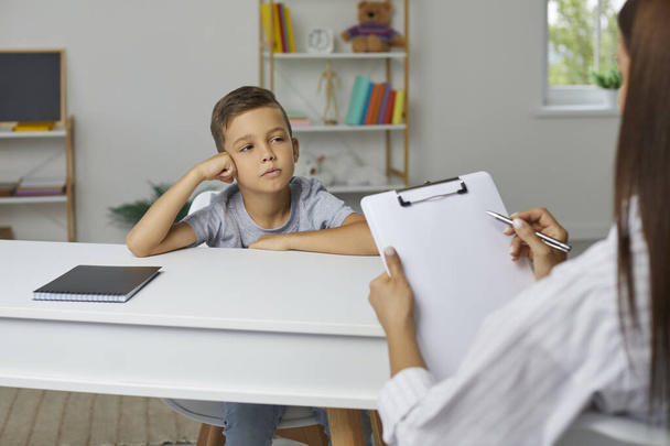 School counselor, psychologist or teacher having conversation with little child boy, holding clipboard, asking questions of personality development test and taking notes. Psychology, education concept - Fotó, kép