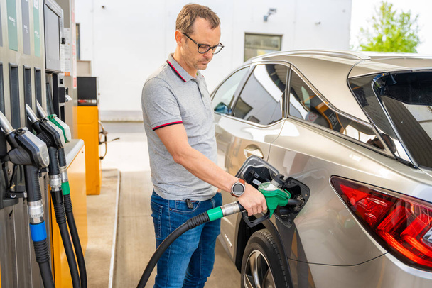 Řidič plní drahý benzin na samoobslužné čerpací stanici v Evropě. Kvalitní fotografie - Fotografie, Obrázek