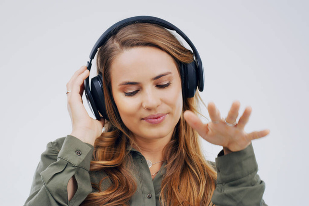 Woman, studio or dancing with headphones and hand for subscription, streaming or music with happiness. Female student or celebrate on backdrop with audio for podcast, happy with sound in California. - Photo, Image