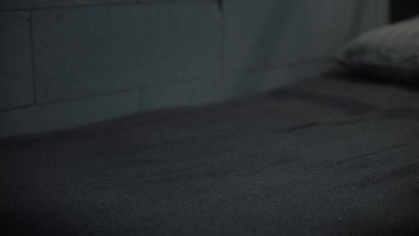 Prise de vue statique d'un prisonnier mettant un uniforme orange de prison et une serviette de bain sur le lit. Un criminel ou un détenu coupable purge une peine d'emprisonnement en prison. Centre de détention ou établissement correctionnel. Système judiciaire. - Séquence, vidéo