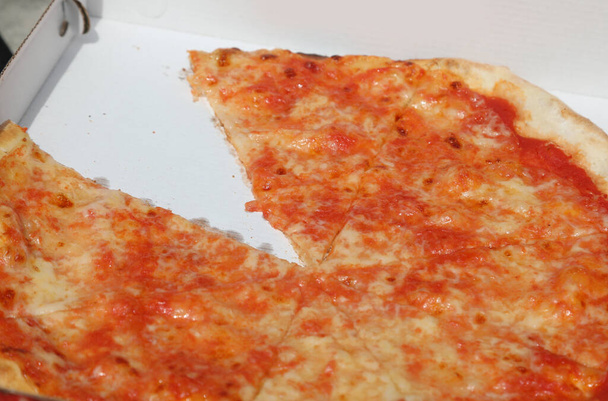 Pizza Margherita à emporter avec mozzarella et sauce tomate dans une boîte en carton avec une tranche manquante déjà consommée - Photo, image