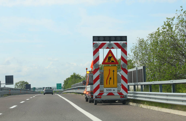 Автодорожный грузовик с дорожным знаком для предупреждения о сужении дороги - Фото, изображение
