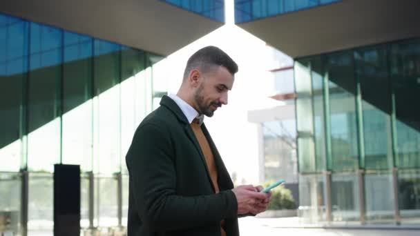 Un jeune homme d'affaires caucasien souriant portant un costume et une cravate est debout devant le bâtiment de la zone de travail. geste inspirant en regardant la caméra extérieure - Séquence, vidéo